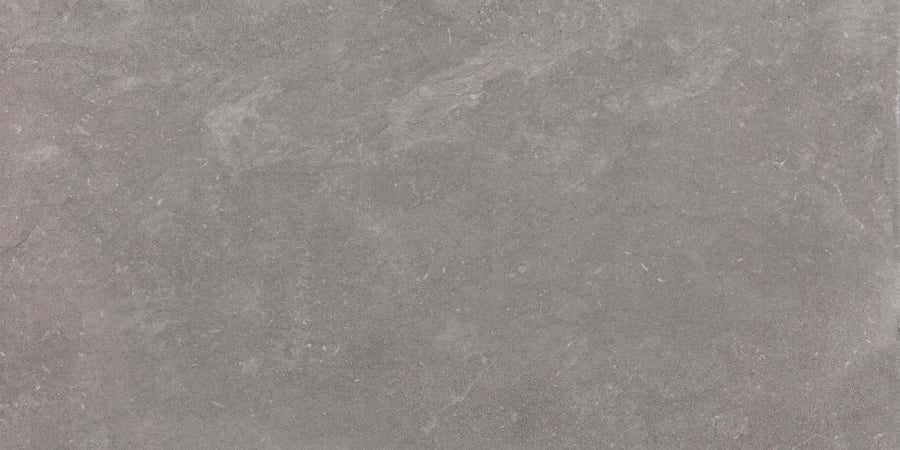 The Revolve 12x24 Rectified Porcelain Tile features a uniform gray concrete look with a slightly rough, stone-like texture, subtle natural patterns, and faint white plus dark gray patches for a contemporary finish.