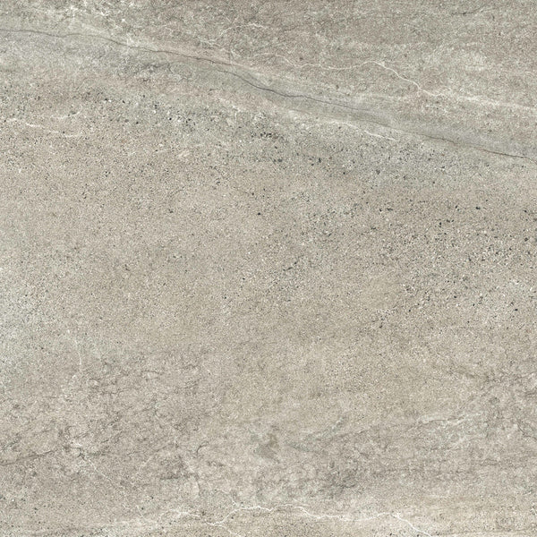 A close-up of the Santorini 24x24 Porcelain Tile shows its textured gray stone-effect surface with subtle white veining and speckled patterns, capturing the tactile elegance of natural marble or granite.
