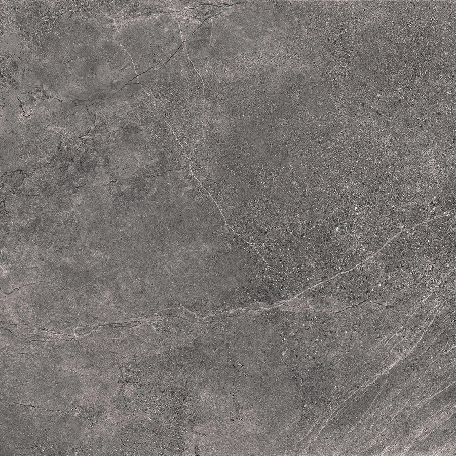 A close-up of Santorini 24x24 Porcelain Tile reveals a dark gray stone-effect surface with subtle white veins, featuring tactile elegance and a slightly rough, speckled texture.