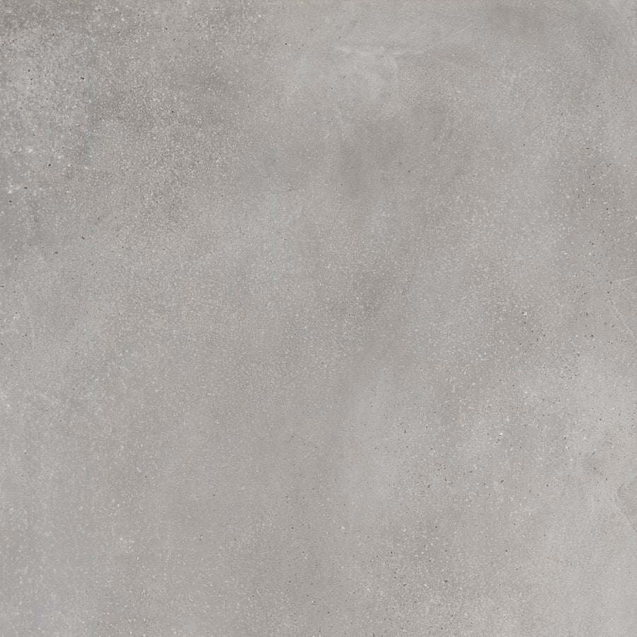 A close-up of Portland 24x24 Porcelain Tile reveals a light gray textured concrete look with subtle color variations and scattered speckles, highlighting authentic surface imperfections.