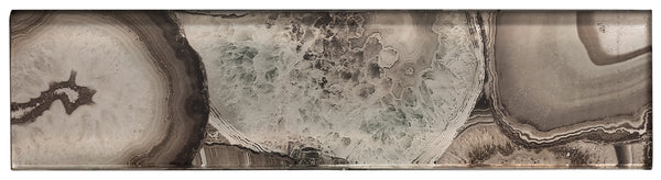 The Magical Forest 3x12 Glass Tile is a rectangular slab with layered agate patterns in brown, beige, and gray tones, featuring crystalline and banded textures that mimic the look of semi-precious stone.