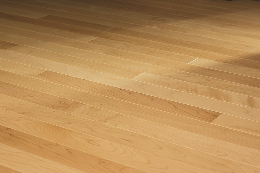 Close-up of Acadia 3 1/4" Hard Maple Hardwood shows a clean, light-toned floor with visible grain and natural variations. Durable planks are arranged horizontally and evenly spaced, highlighting its traditional hardwood floor appeal.