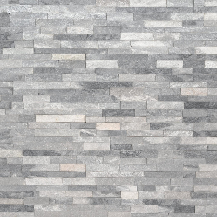 A close-up of a wall featuring Landscape 4.5x16 Natural Stone Ledger Panel tiles in gray, arranged in a staggered brick pattern with varied shades and subtle surface texture for a modern look.