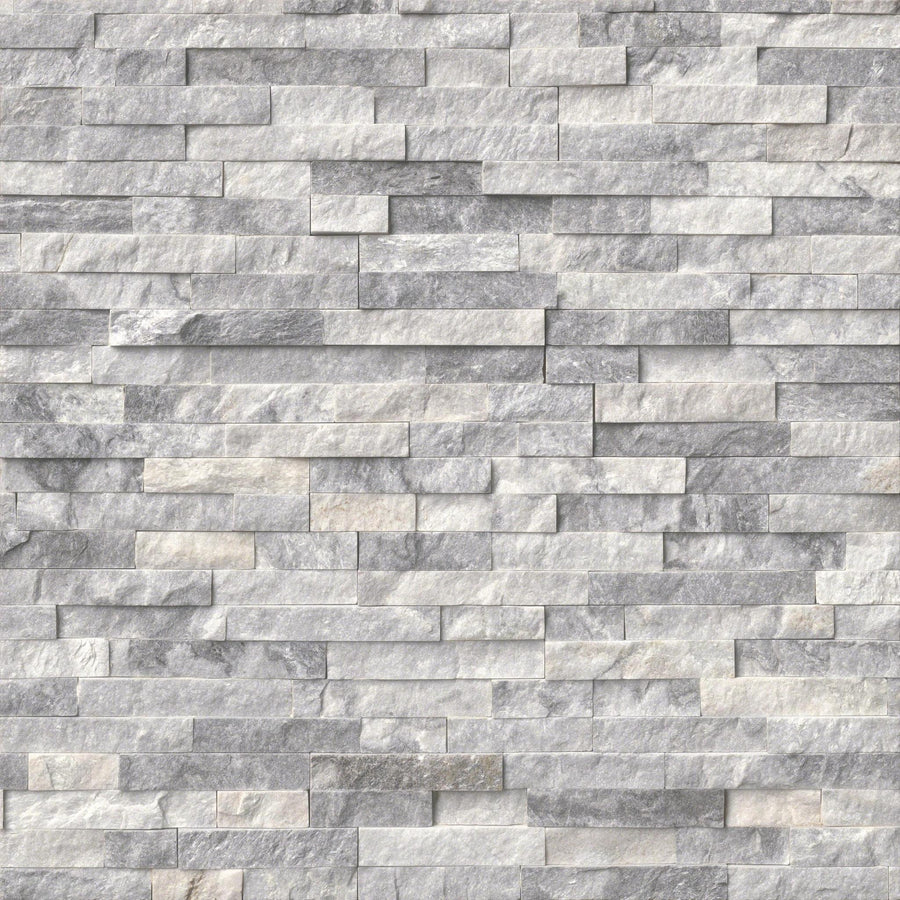 A close-up of a wall featuring Landscape 6x24 Natural Stone Ledger Panel tiles in light gray, arranged in a staggered brick pattern. The split-face stones have a rough texture and subtle shade variations for a dynamic, modern look.