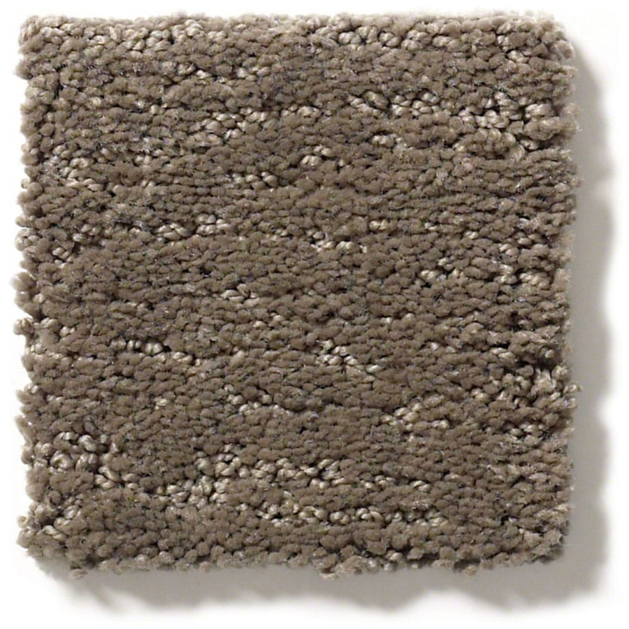 A square sample of Sketch On Trend Carpet in light brown features a dense, plush pile and textured surface. Soft, thick fibers deliver a cozy, cushioned look that’s stylish and inviting.