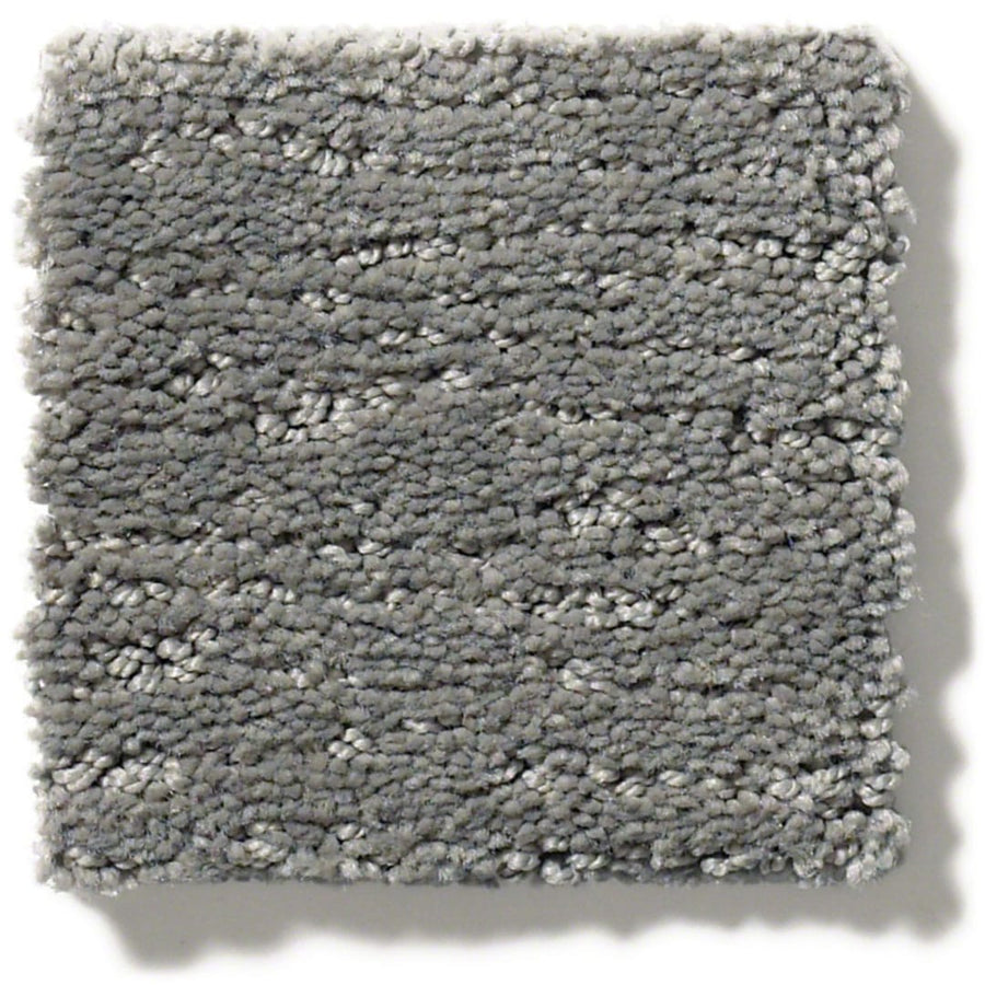 A square sample of Sketch On Trend Carpet in light gray features a soft, plush texture and thick, densely packed, soil and stain-resistant nylon fibers in nature-inspired neutrals for a cozy look.