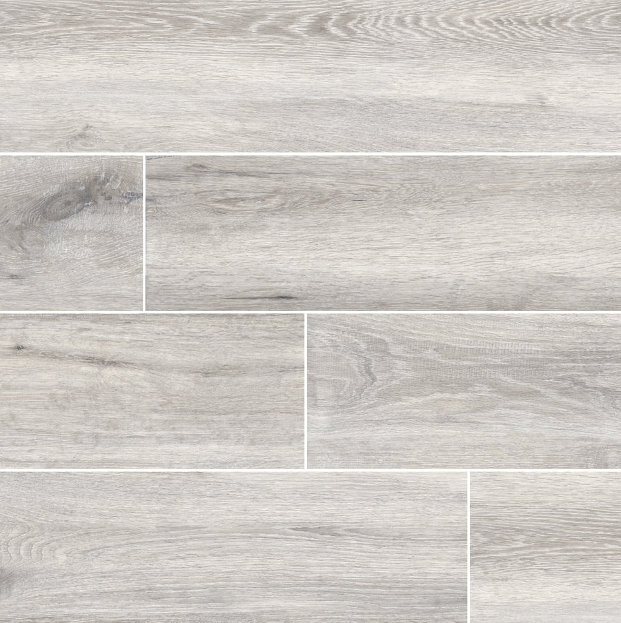 The Antonius 6x36 Porcelain Tile features a light gray hue with wood grain textures and natural knots in a staggered layout, offering realistic wood appeal. Ideal for elegant spaces, it combines style and durability.