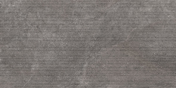 A close-up of the Santorini 12x24 Grooves Deco Porcelain Tile, showcasing its textured gray stone-effect surface with subtle cracks, speckles, and faint horizontal lines that mimic concrete or natural rock.
