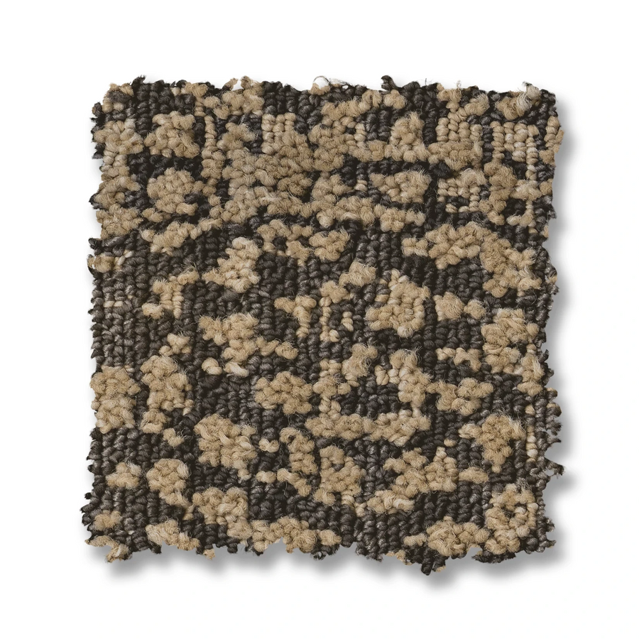 A square swatch of Batique On Trend Carpet displays abstract patterns in beige and dark brown with dense, raised textured fibers on a white background.