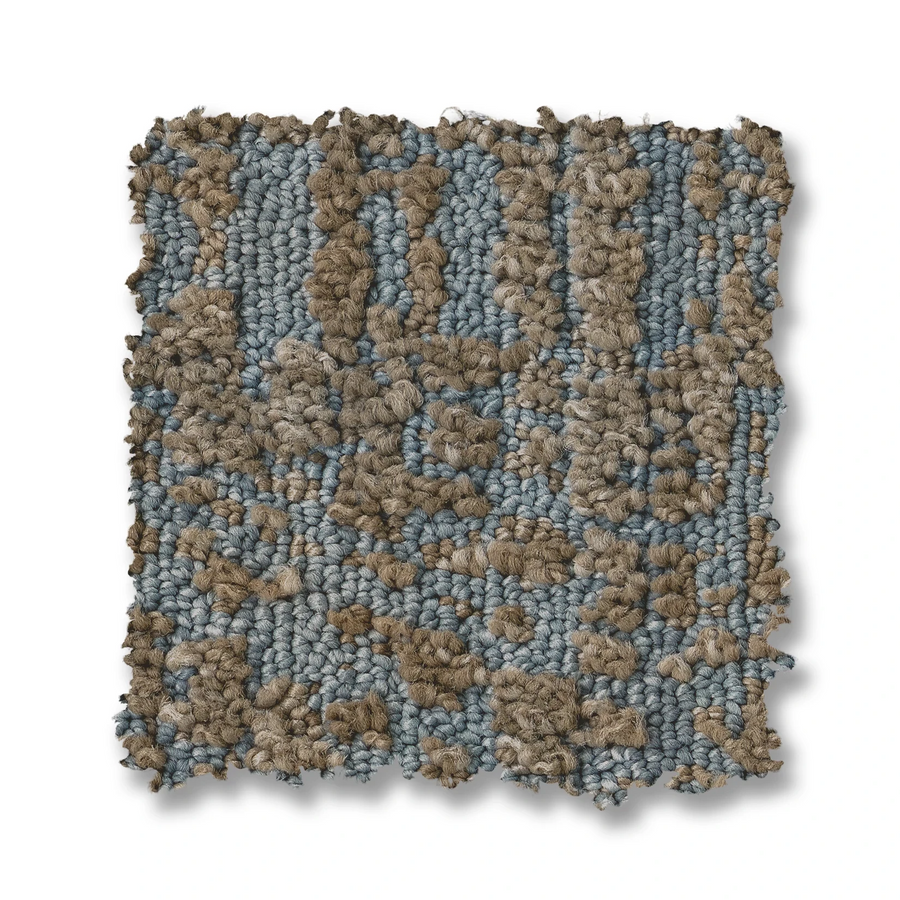A square swatch of Batique On Trend Carpet displays beige and light blue looped fibers in an abstract, irregular textured pattern with uneven, slightly frayed edges.