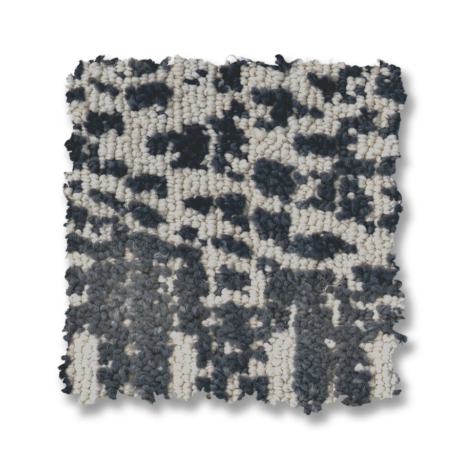 The Batique On Trend Carpet features a square swatch with a textured, chunky woven fabric and an abstract mottled pattern in black, gray, and white tones. The surface varies in density for added visual interest.