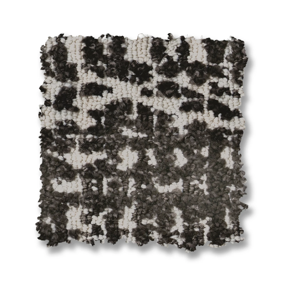 A square swatch of Batique On Trend Carpet showcases a handwoven, black and white textured pattern with thick, irregular yarns creating a raised, bumpy surface.