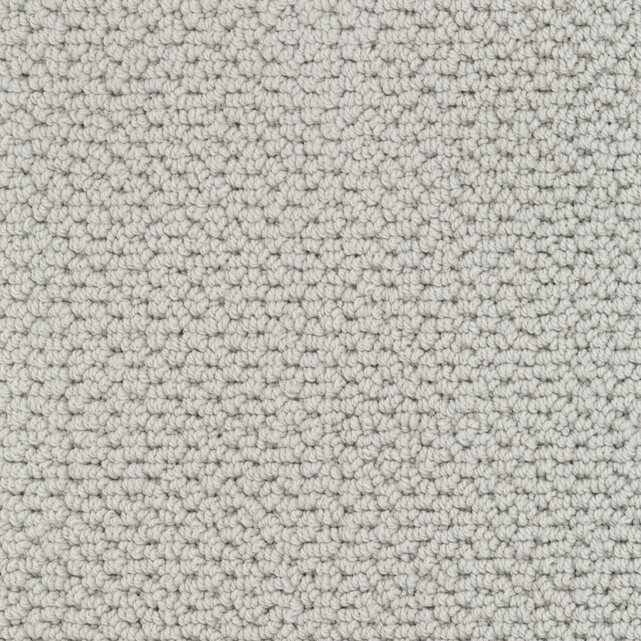 Close-up view of Beachfront Berber Carpet in light gray. This looped-pile performance carpet features small, uniform loops and a pebble-like, textured surface in neutral natural tones for a soft, even pattern.