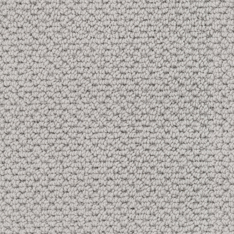 Close-up view of Beachfront Berber Carpet, a textured light gray performance carpet made from EnVision nylon with tightly woven loops for a uniform, slightly raised surface in neutral natural tones.