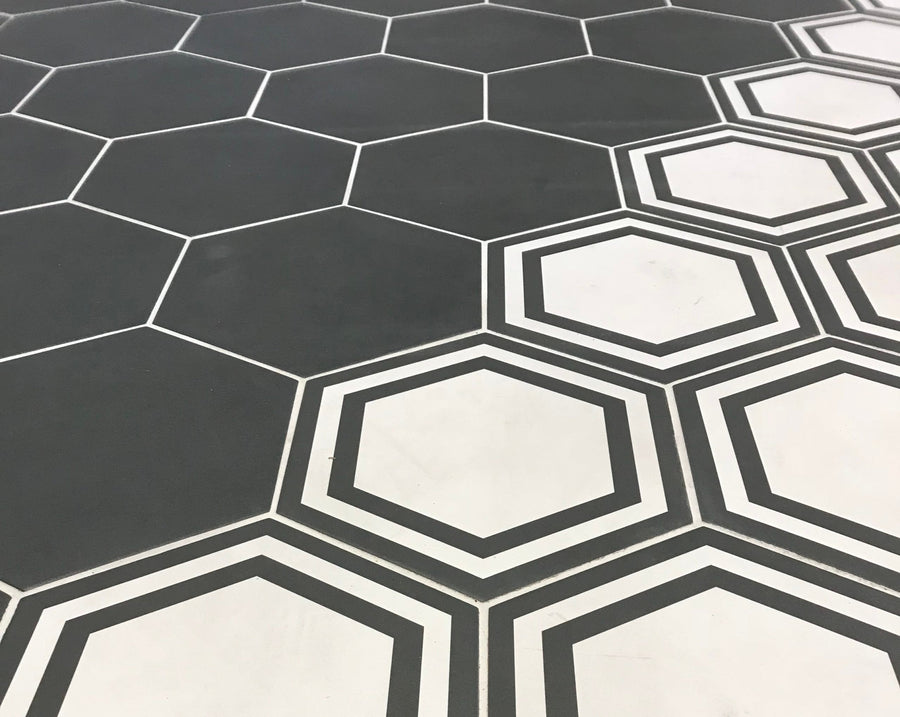 A floor showcases 8x9 Glazed Hex Tile in black hexagons on the left and white hexagons outlined in black on the right, creating a seamless transition and bold geometric look for modern interiors.