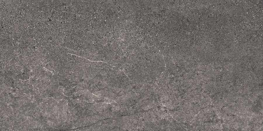 Santorini 12x24 Porcelain Tile features a gray stone look with a rough, speckled texture and subtle white veining, capturing the tactile elegance of natural surfaces.