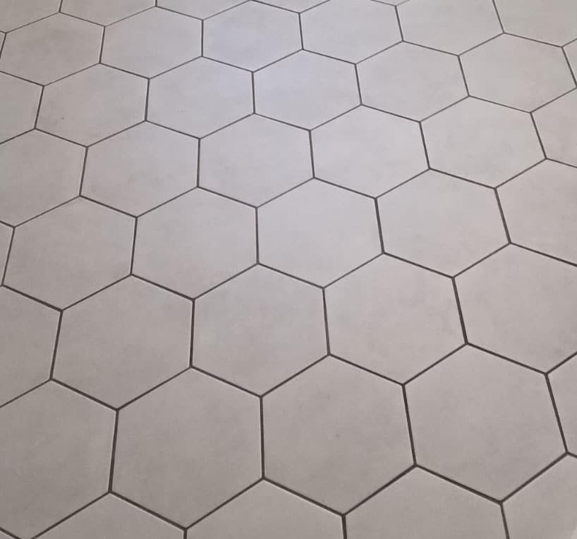 8x9 Glazed Hex Tile arranged in a honeycomb pattern with dark grout lines adds a geometric, modern touch to any space. The clean, evenly spaced tiles bring stylish flair and contemporary decor to your room.