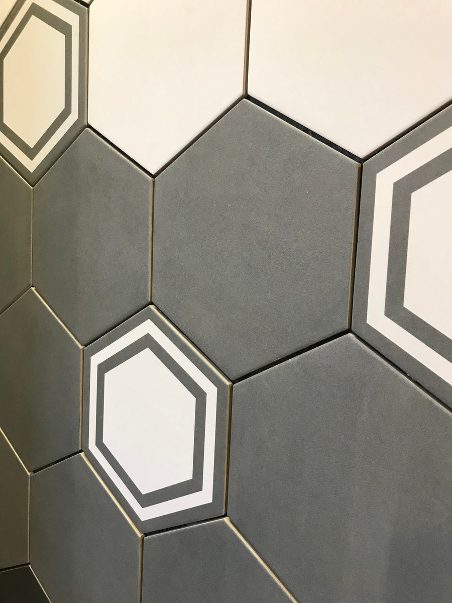 The 8x9 Glazed Hex Tile adds a modern geometric style to any space with its repeating pattern of solid gray, solid white, and white tiles outlined in gray hexagons—ideal for striking, contemporary wall decor.