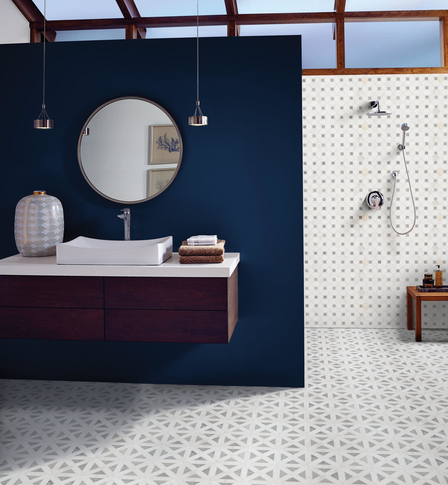 Modern bathroom featuring a floating dark wood vanity, round mirror, white vessel sink, blue accent wall, Dolomite Geometrica Mosaic Natural Stone backsplash tile, geometric floor, and open shower with small square tiles and a wooden bench.