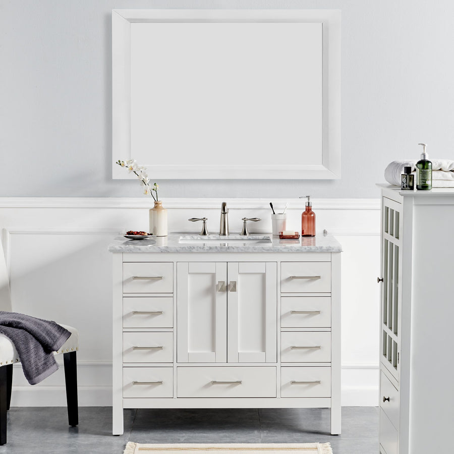 The Aberdeen 42" Vanity features a modern white finish, marble countertop, double handles, silver faucet, and a large rectangular mirror. Essentials like soap, a plant, and towels are neatly arranged on and around this elegant bathroom piece.