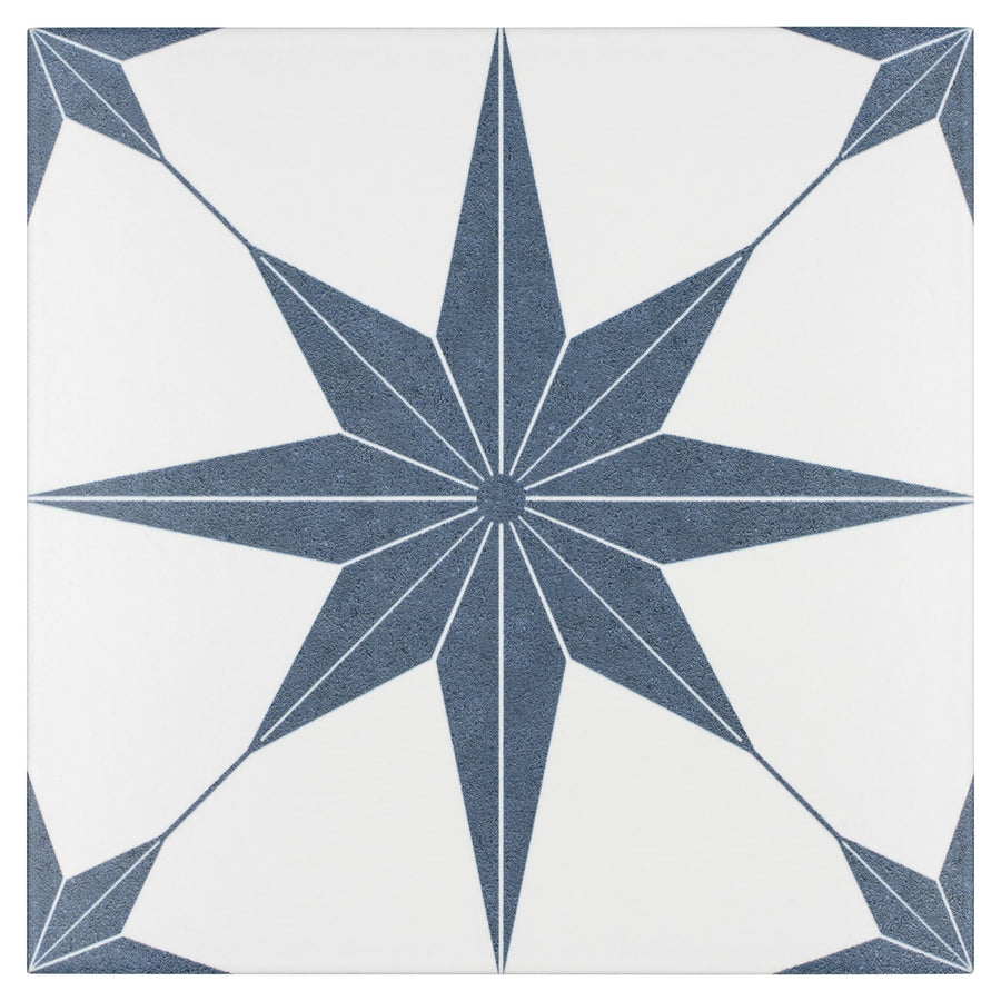 The Stella 9 3/4 x 9 3/4 Patterned Tile features a navy blue eight-pointed star with white lining at the center of a white geometric tile, with the star’s tips reaching toward the tile’s edges and corners.
