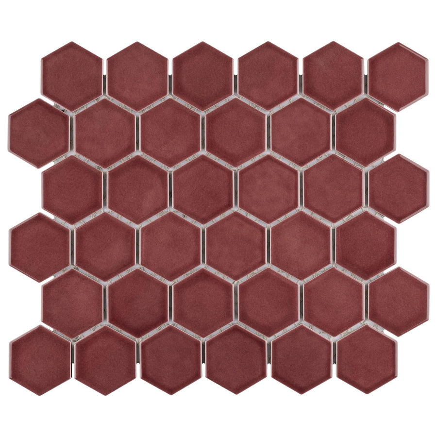 The Tribeca 2" Hex Glossy Mosaic Tile features red hexagonal porcelain pieces in a grid pattern with visible grout lines, creating a bold geometric look on a white background.