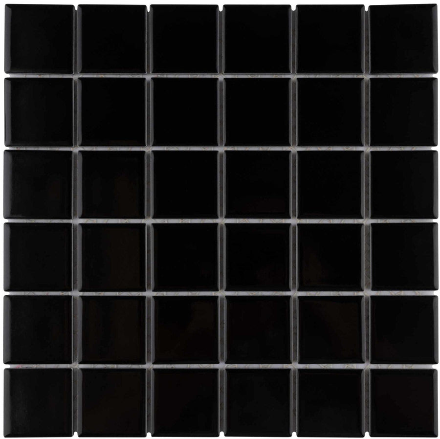 The Metro Quad Mosaic Tile features a grid of glossy black porcelain tiles in a 6x6 layout with slim grout lines, delivering a neat and uniform backsplash surface.