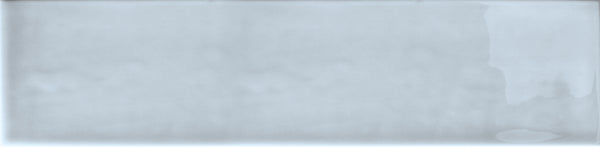 The Essence 2.5x10.5 Subway Tile is a rectangular, light gray ceramic tile with a glossy, textured finish and slight shade variations, featuring subtle, irregular darker gray patches on the right edge.