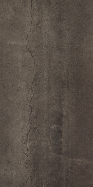 A close-up of Platform 12x24 Porcelain Tile shows its dark, textured concrete look with a prominent vertical crack, metallic accents, and a rough, weathered surface for contemporary style.