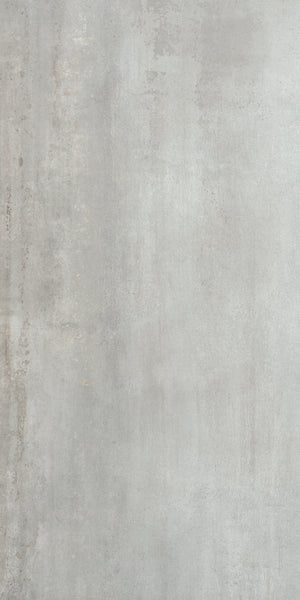 A close-up of Platform 24x48 Porcelain Tile reveals a smooth, light gray finish with subtle texture and faint vertical streaks, offering a metallic look that enhances its minimalist and industrial appeal.