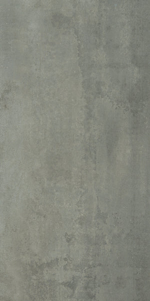 The Platform 12x24 Porcelain Tile features a textured gray surface with uneven coloring, subtle stains, and visible patches, delivering an industrial, weathered look inspired by aged metal plates and a muted metallic finish.