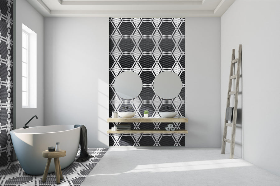 Modern bathroom featuring a freestanding bathtub, two round mirrors above wooden shelves, an accent wall with Evolve Hexagon Flower Mosaic Tile in black and white, a wooden stool, towel, and ladder against a white wall.