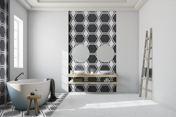Modern bathroom featuring a freestanding bathtub, two round mirrors above wooden shelves, an accent wall with Evolve Hexagon Flower Mosaic Tile in black and white, a wooden stool, towel, and ladder against a white wall.