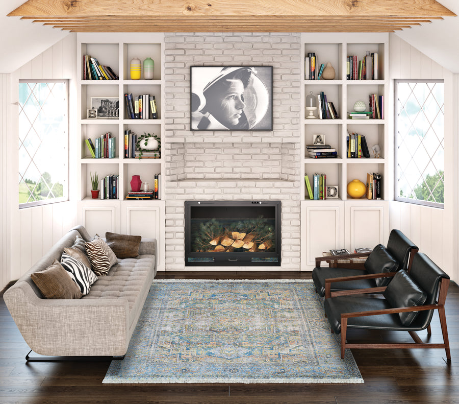 A modern living room with a gray sofa, two black armchairs, the Halli Antique Lavar Area Rug, a white brick fireplace, built-in bookshelves, and a TV above the mantel playing a black-and-white movie scene.