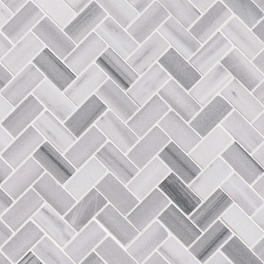 A close-up of Herringbone Mosaic Natural Stone, featuring rectangular gray and white tiles with subtle shade variations and smooth grout lines—an ideal choice for a stylish kitchen backsplash.