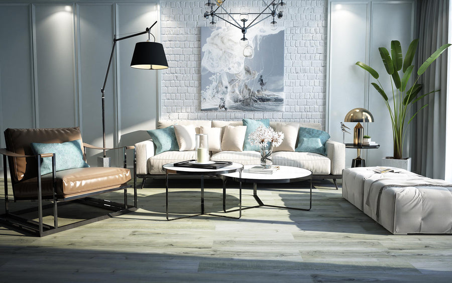 A modern living room features a white sofa, brown leather armchair, round coffee table, floor lamp, potted plant, large wall art, and stylish minimalist decor. The Hydro Vinyl 7" Waterproof Vinyl Plank flooring adds a realistic hardwood look.