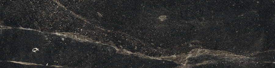 The Ibla 12x48 Large Format Porcelain Tile features a dark, textured surface with subtle beige and white streaks, creating a natural, rugged look—perfect for modern interiors seeking earthy elegance.