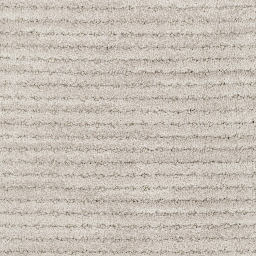 Close-up of Imagine Pet Friendly Carpet in light beige, showing textured wool with horizontal ribbed lines and a plush, soft surface. The uniform pattern emphasizes its handmade authenticity in every fiber.