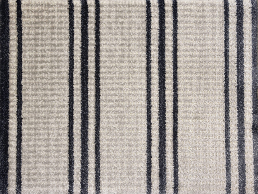 Close-up of Jazabella On Trend Carpet, a textured beige surface with a grid design and multiple vertical black and dark gray stripes of varying thickness on its stain-resistant finish.