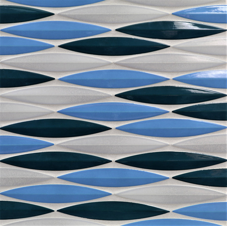 The Ka-Nu Keel 3D Mosaic Tile features a geometric pattern of elongated diamonds in alternating dark blue, light blue, and white, arranged in horizontal rows on a subtly glazed textured ceramic surface.