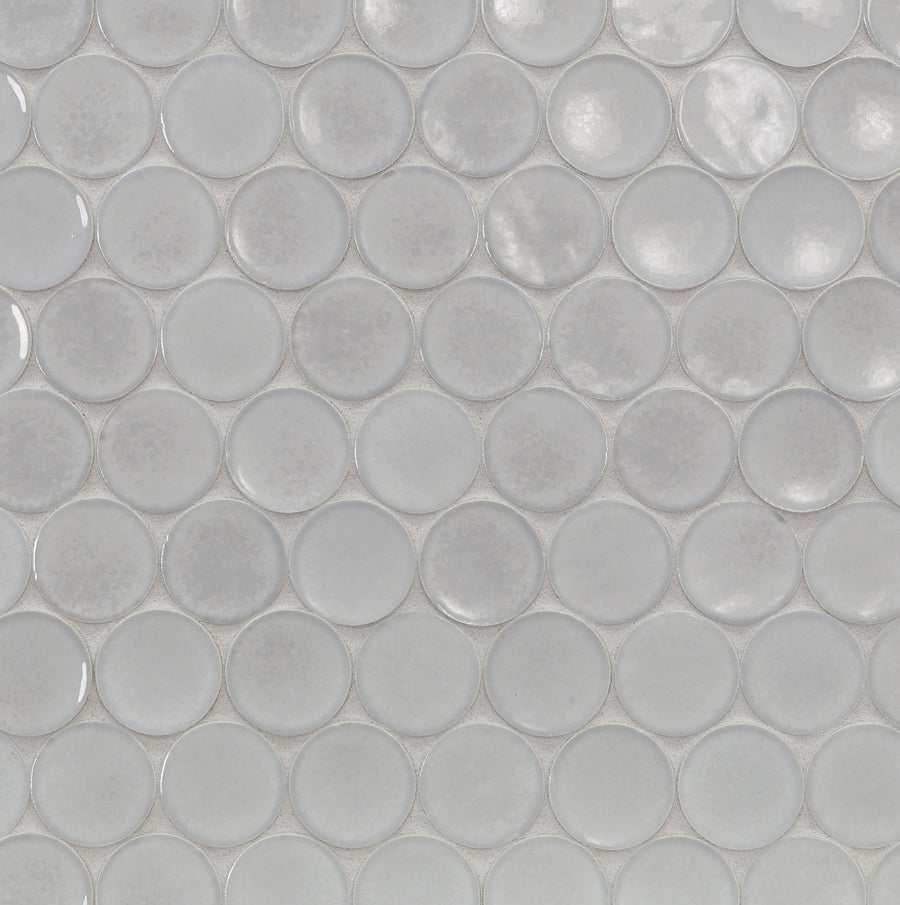 Close-up of a tile surface featuring the Ka-Nu Buoy 2" Pennyround Mosaic Tile, showcasing glossy, light gray ceramic tiles with subtle reflections and gentle tonal variations in a repeating mosaic pattern.