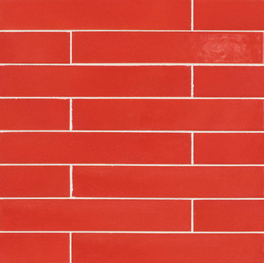 A close-up view of a wall featuring Ka-Nu 1 5/8 x 9 1/2" Plank Ceramic Tile in glossy red, arranged horizontally in a brick pattern with thin white grout lines.