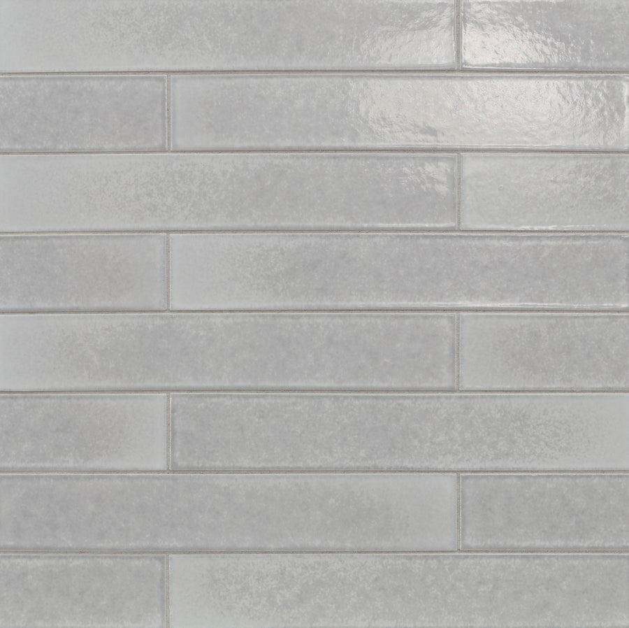 Ka-Nu 1 5/8 x 9 1/2" Plank Ceramic Tile features elongated rectangular ceramic tiles in glossy light gray, arranged horizontally in a brick pattern with soft color variations and smooth joints.