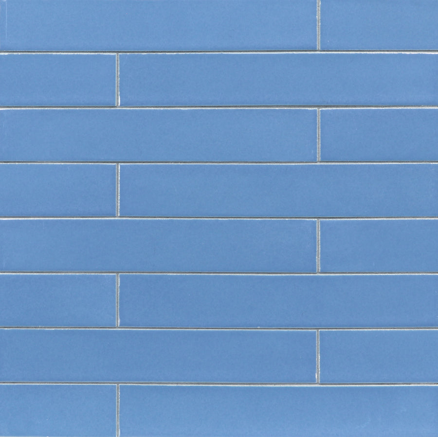 A close-up view of a wall featuring Ka-Nu 1 5/8 x 9 1/2" Plank Ceramic Tiles in vibrant colors, arranged horizontally in a brick pattern and separated by thin white grout lines.