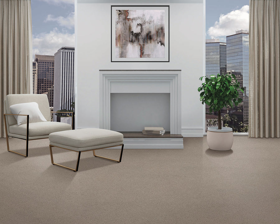 A modern living room features the Dynamic Display Family Friendly Carpet, a white armchair and ottoman, potted plant, abstract art above a white fireplace, large windows, and city views—a decorator’s dream.