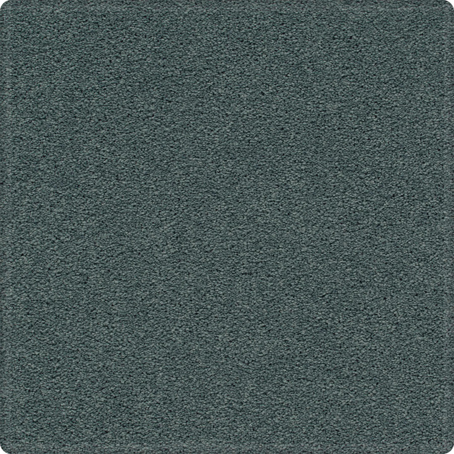 A close-up of the Dynamic Display Family Friendly Carpet shows its soft, even pile, rounded corners, and easy-care durability—making this textured dark teal carpet a decorator’s dream.