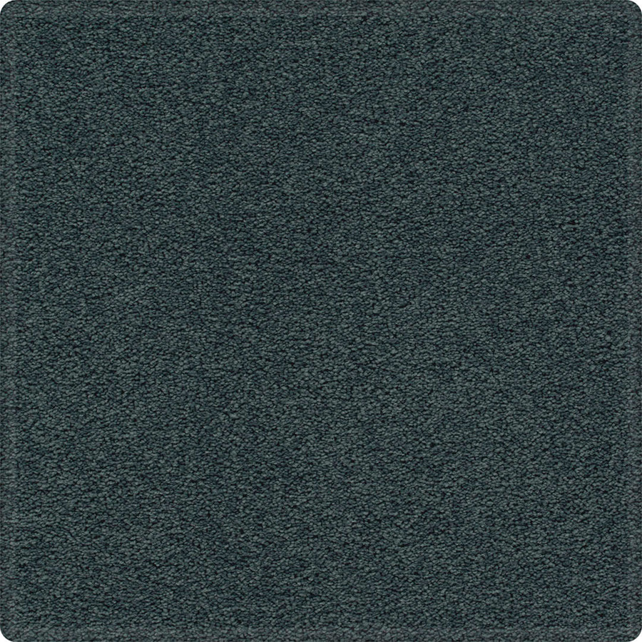 A close-up of the Dynamic Display Family Friendly Carpet shows dense, dark gray textured fibers with rounded corners, offering both plush comfort and easy-care durability—an ideal choice for stylish decorators.
