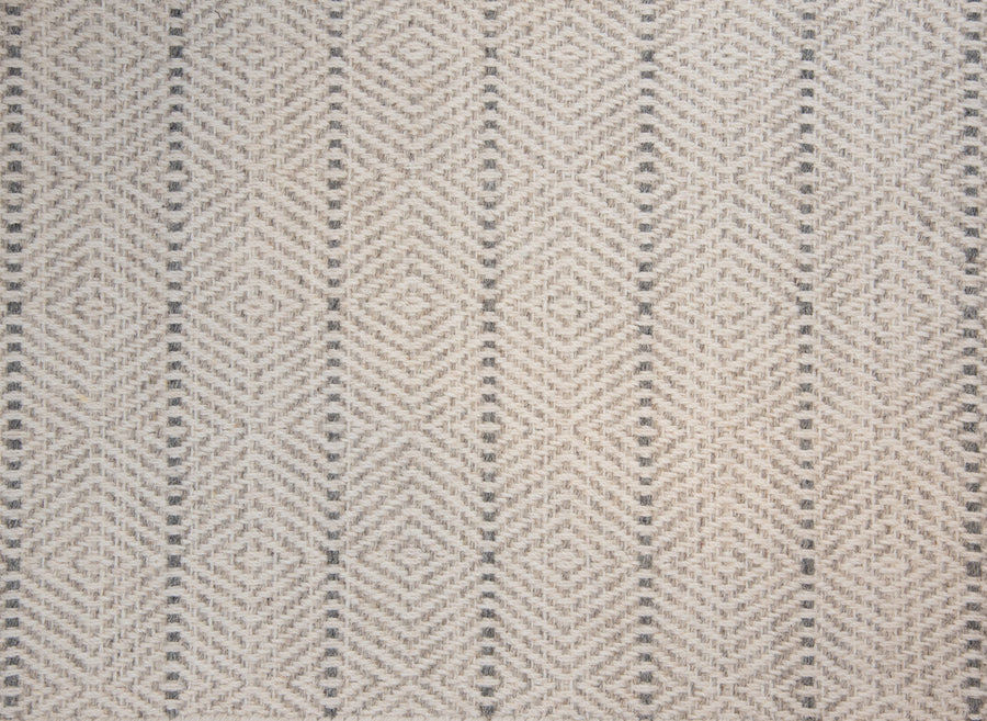 A close-up of the Kariba On Trend Wool Carpet shows a soft, slightly raised woven texture with a repeating geometric diamond and chevron pattern in beige and light gray, adding elegance to this custom-finished rug.