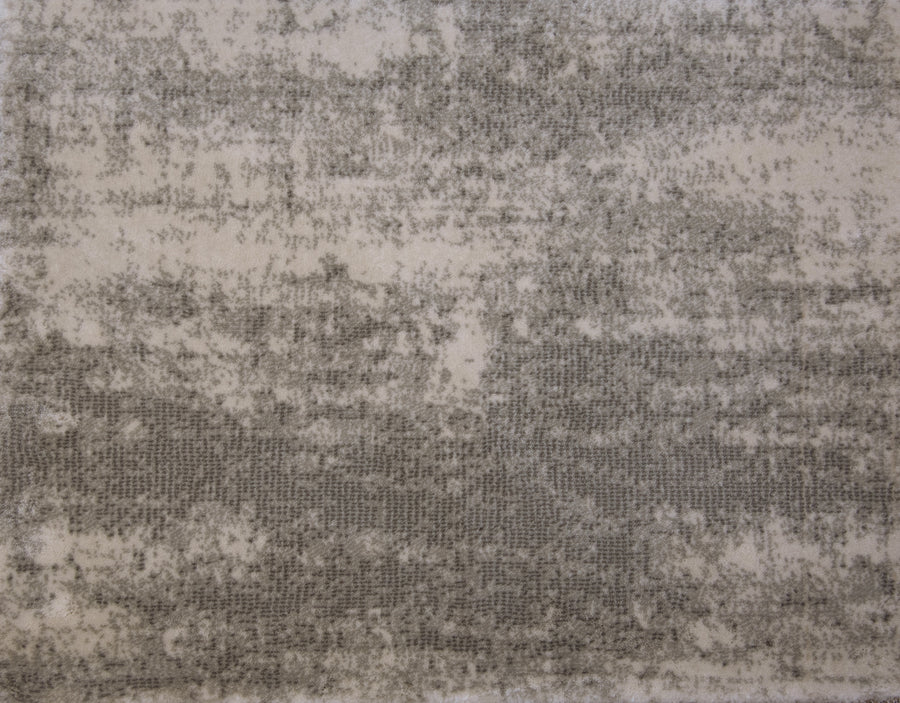 A close-up of Landscape On Trend Carpet showcases its textured, organic-dyed flooring with a mottled gray and beige pattern, featuring contrasting light and dark areas for an abstract, uneven design.