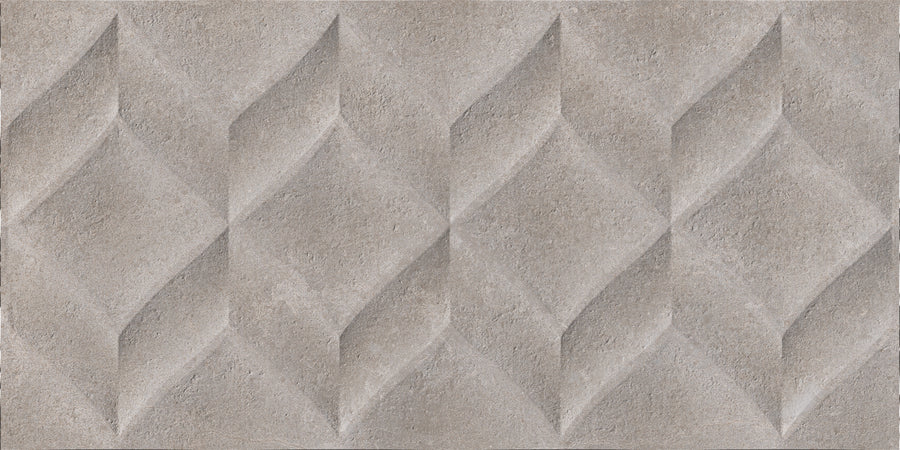 The Omni 12x24 Rectified Glazed Ceramic Tile features a textured, three-dimensional repeating diamond pattern with faceted relief in a muted, stone-like gray finish.